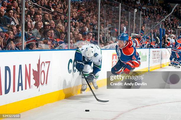 Taylor Hall of the Edmonton Oilers soars through the air trying to get the puck against Keith Ballard of the Vancouver Canucks at Rexall Place on...