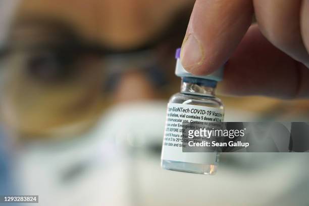 Doctor holds vials containing the Pfizer/BioNTech vaccine stand during vaccinations at a nursing home of the DRK on the first day of the nationwide...