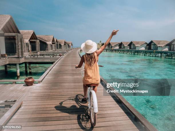 young woman with bicycle on wooden pier in the maldives - maldives stock pictures, royalty-free photos & images