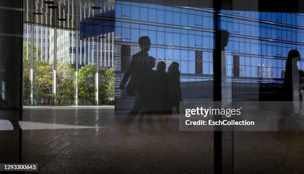 office window with reflection of office workers arriving for work - business people sunrise walking through the city stock pictures, royalty-free photos & images