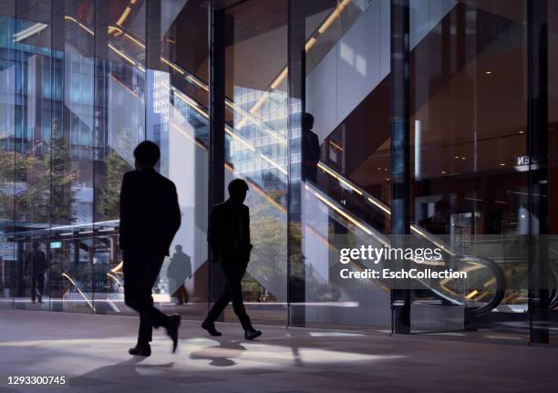 modern office facade with silhouettes of passing office workers - outdoor lounge stockfoto's en -beelden