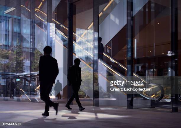 modern office facade with silhouettes of passing office workers - conformity stock pictures, royalty-free photos & images