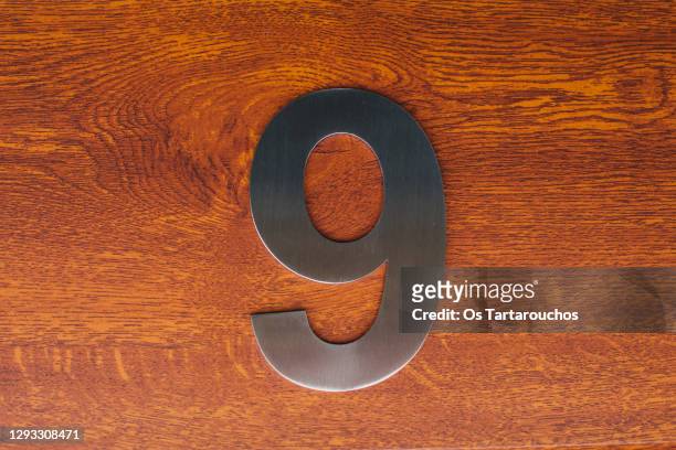 stainless steel number 9 on a wood door background - getal 9 stockfoto's en -beelden
