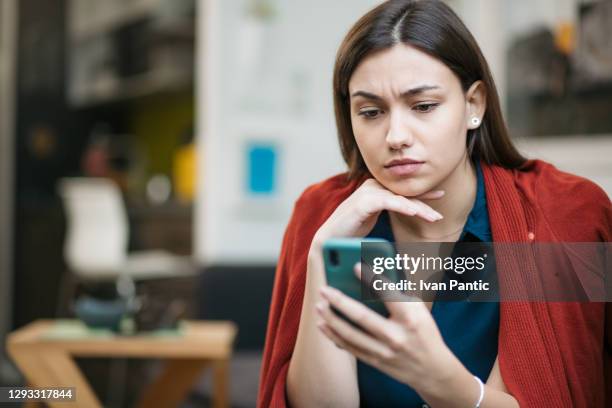 close up of a sad young caucasian woman reading bad news - irritation stock pictures, royalty-free photos & images