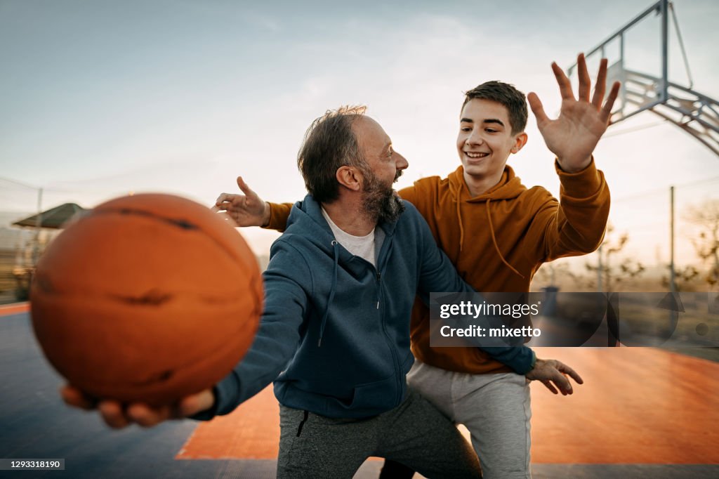 Vater spielt mit seinem Sohn Basketball