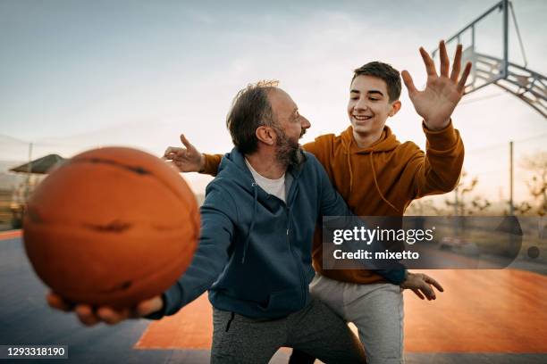 father playing basketball with his son - teen son stock pictures, royalty-free photos & images