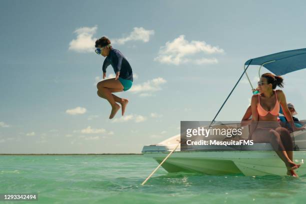 garçon sautant dans la mer pendant le tour de hors-bord - jumping of boat photos et images de collection
