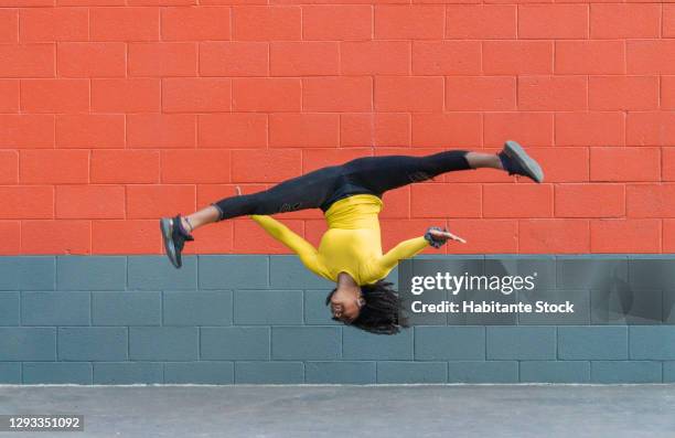 african-american girl jumping and performing gymnastic moves - acrobatics gymnastics stockfoto's en -beelden