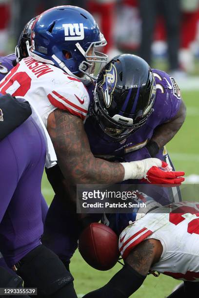 Running back Gus Edwards of the Baltimore Ravens fumbles the ball for a turnover against free safety Logan Ryan of the New York Giants during the...