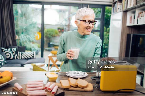 senior woman having a breakfast at home - old toaster stock pictures, royalty-free photos & images