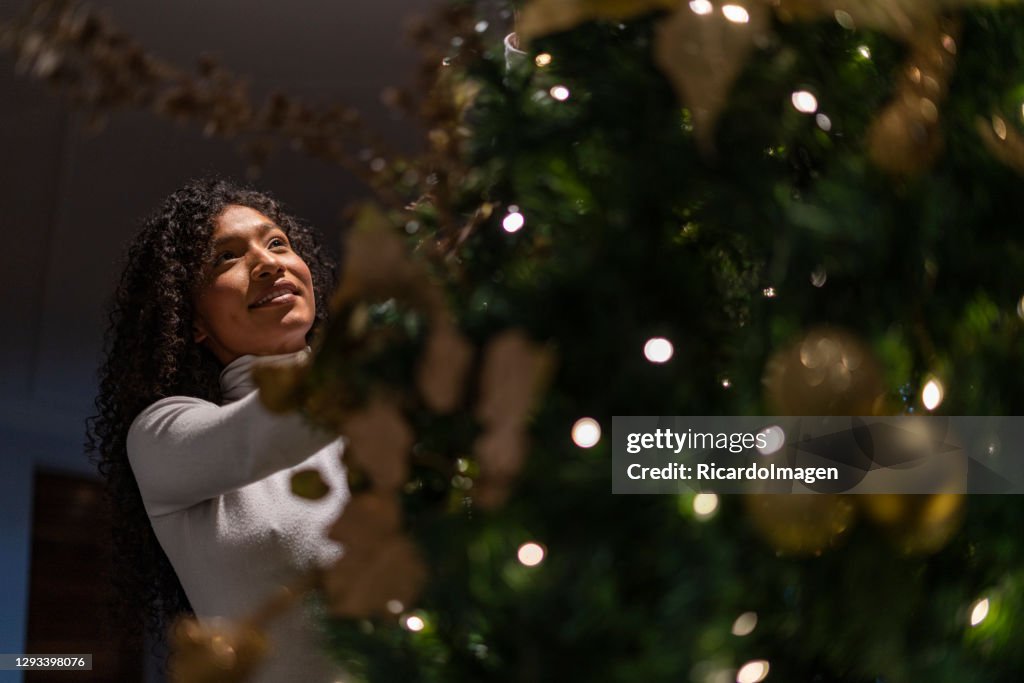 Woman is at home decorating the Christmas tree