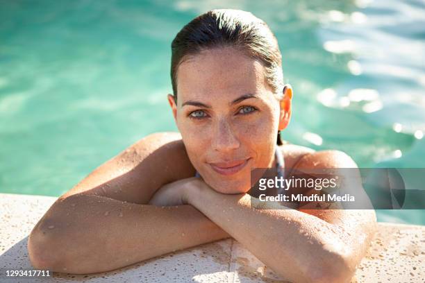 beautiful caucasian woman leaning on poolside - women by pool imagens e fotografias de stock