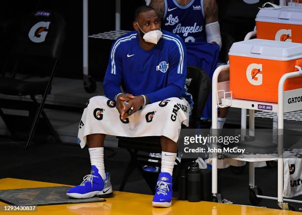 LeBron James of the Los Angeles Lakers wears a face mask on the bench in a game against the Minnesota Timberwolves at Staples Center on December 27,...