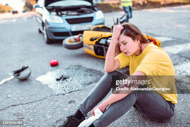 frau noch unter schock, nachdem sie von auto mit motorrad getroffen - schnittwunde stock-fotos und bilder