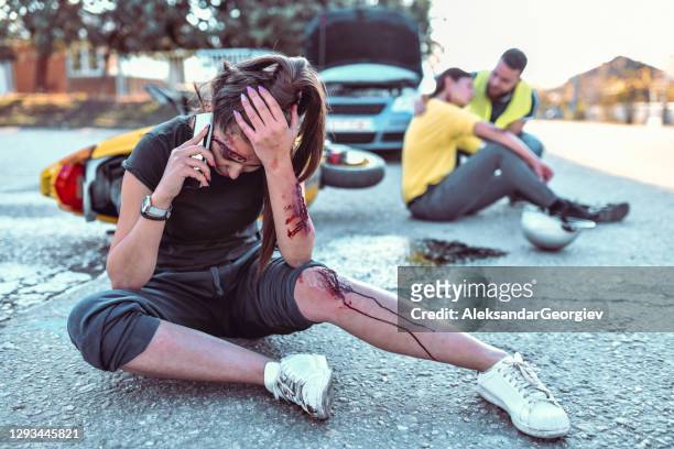 female calling ambulance while injured in car accident - motorcycle accident stock pictures, royalty-free photos & images