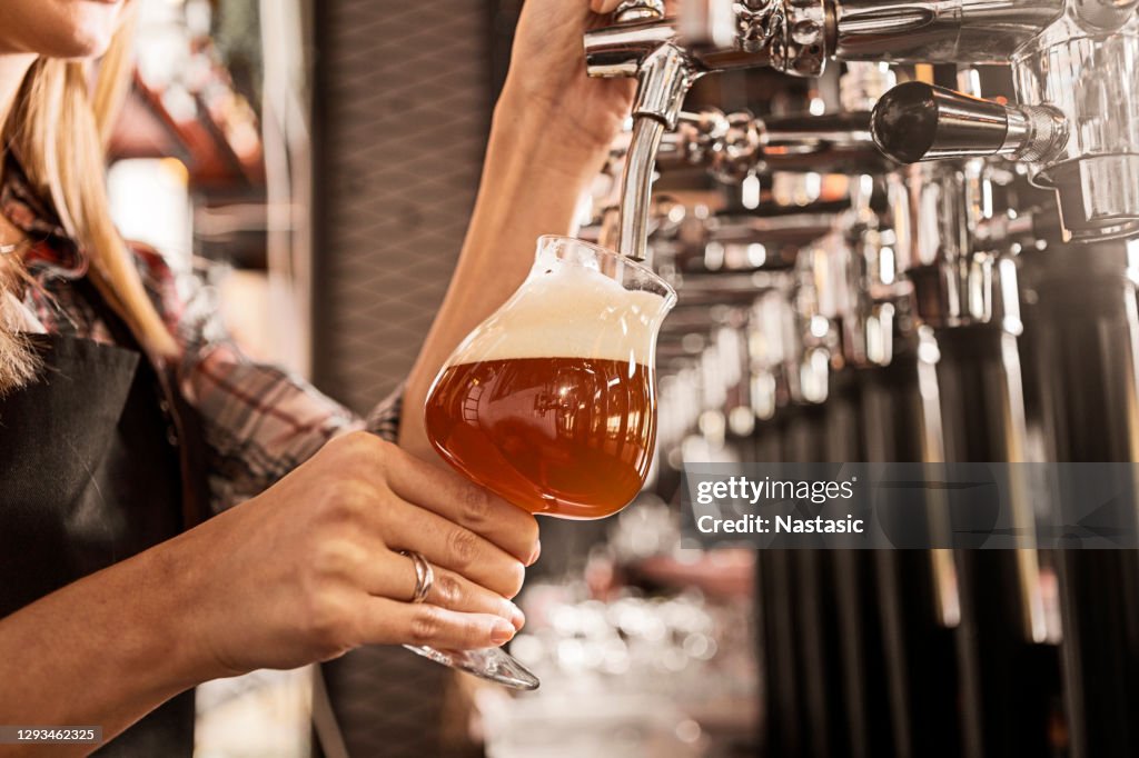 バーのビールタップで女性バーテンダーの手