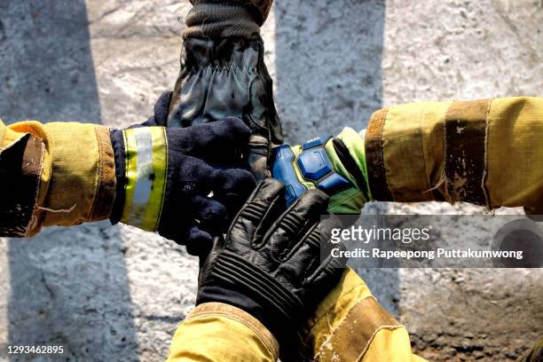 members of the fire department putting hands and show that they are a strong group teamwork - red suit stockfoto's en -beelden