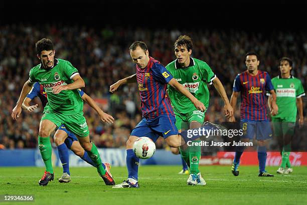 Andres Iniesta of FC Barcelona strikes the ball besides Alvaro Gonzalez and Francisco Malia of Racing Santander during the la Liga match between FC...