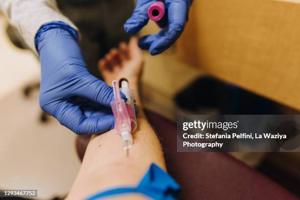 personal perspective of paramedic's hands collecting blood sample from a female's arm - syringe full of blood stockfoto's en -beelden