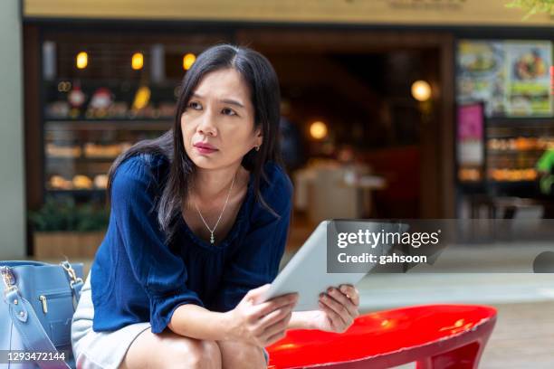 donna depressa che usa tablet digitale all'aperto - asian woman angry foto e immagini stock