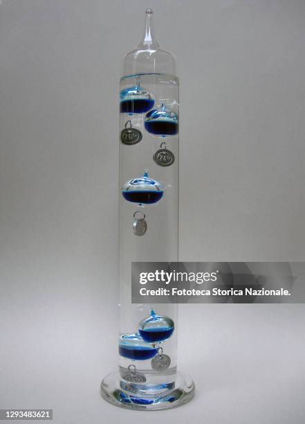 Galileo thermometer with colorful glass bubbles in liquid giving