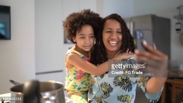 mother and daughter doing a video call while cooking together at home - virtual lunch stock pictures, royalty-free photos & images