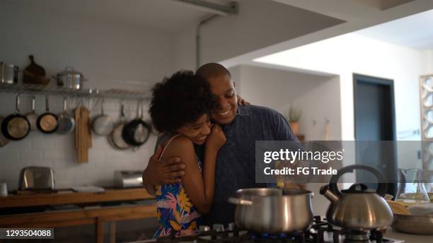 father and daughter embracing while cooking at home - fathers day lunch stock pictures, royalty-free photos & images