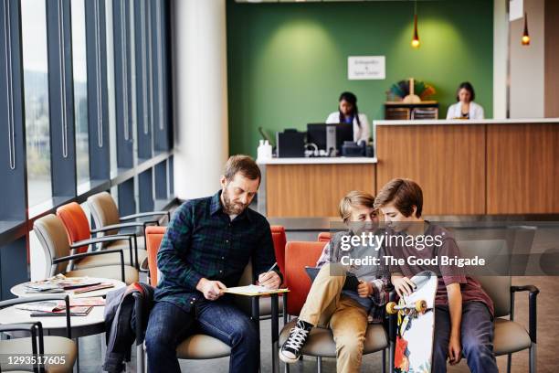 father and sons in hospital waiting room - loungeroom stockfoto's en -beelden