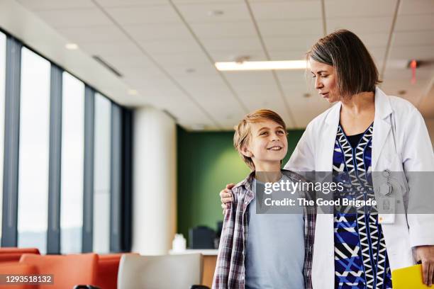 female doctor talking to smiling boy in hospital - child doctor stock pictures, royalty-free photos & images