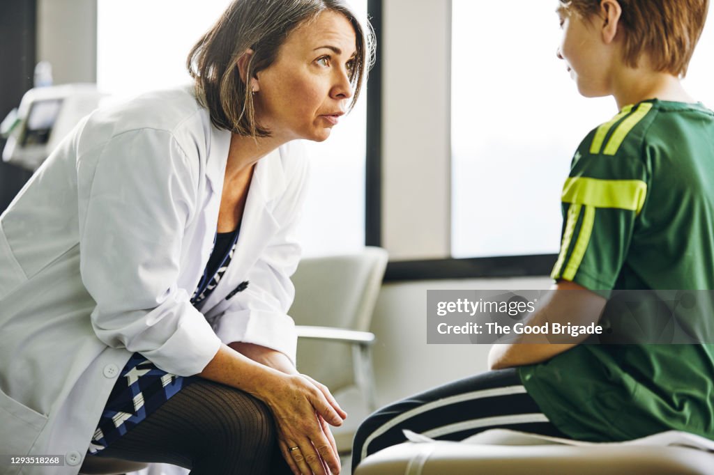 Smiling doctor talking to boy in exam room