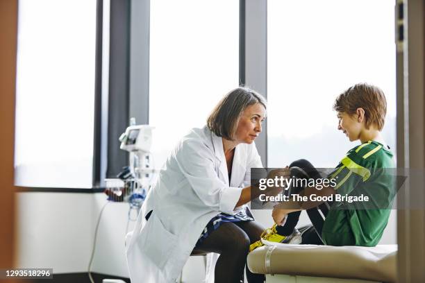 female doctor examining young boy in hospital - male knee stock pictures, royalty-free photos & images