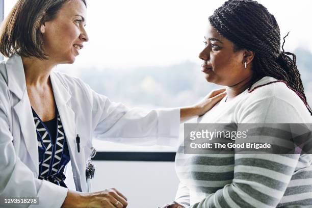 female doctor consoling young woman in hospital - worried doctor stock pictures, royalty-free photos & images