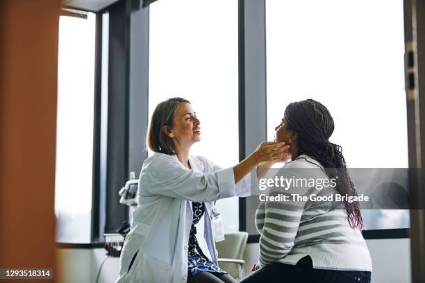 smiling female doctor examining young woman in hospital - human gland stockfoto's en -beelden