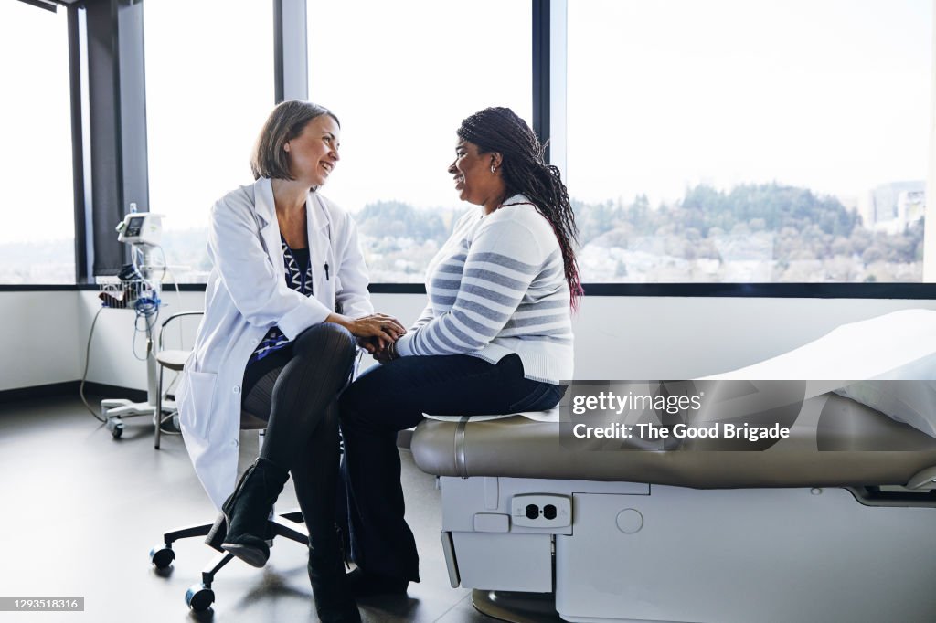 Smiling female doctor talking to woman in hospital
