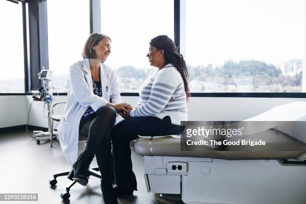 smiling female doctor talking to woman in hospital - talking stock pictures, royalty-free photos & images