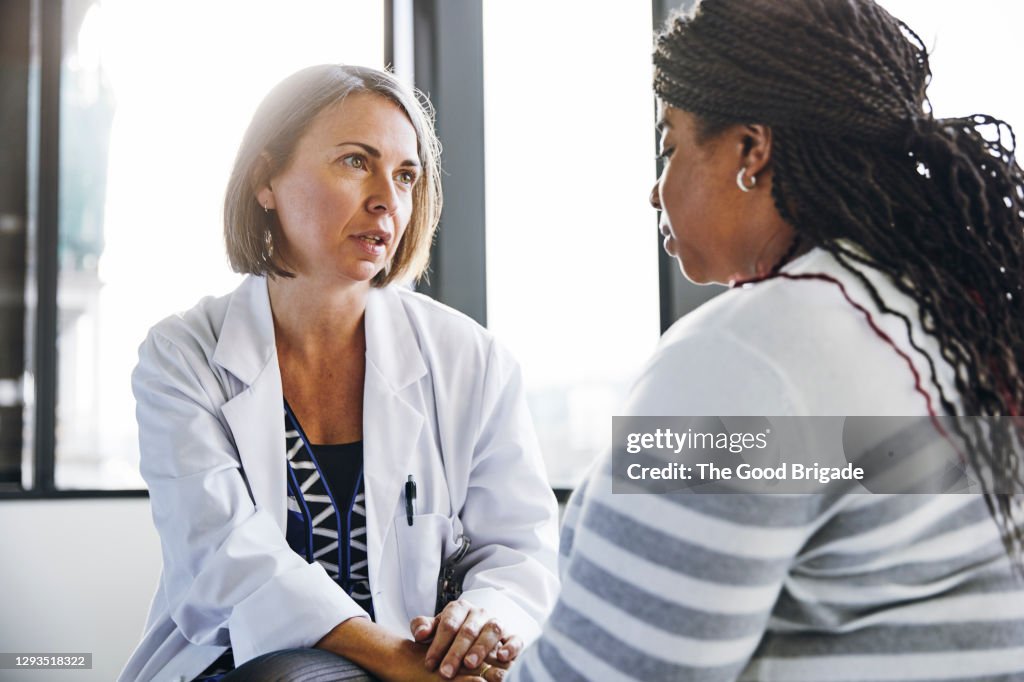 Mature doctor talking to young woman in hospital