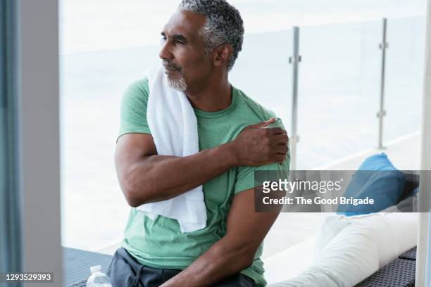 mature man stretching after at home workout - giuntura foto e immagini stock