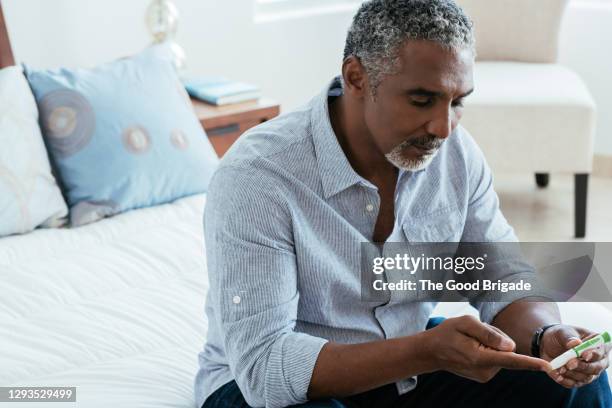 mature man checking diabetes in bedroom - diabète photos et images de collection