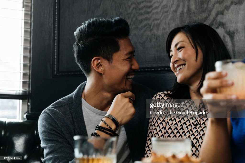 Smiling woman enjoying drinks with friends at restaurant