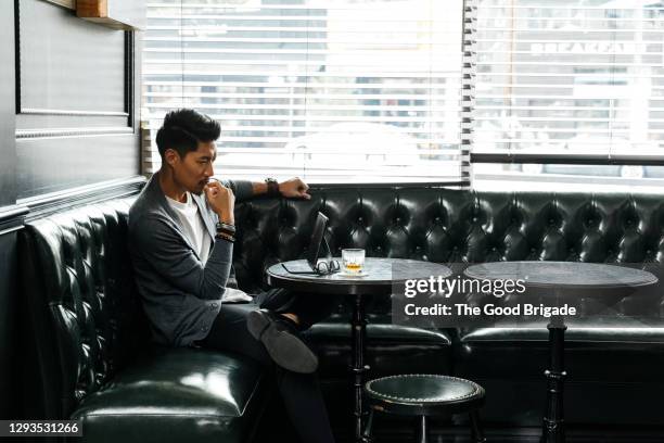 mid adult man looking at digital tablet in restaurant - tablet alcohol stock-fotos und bilder