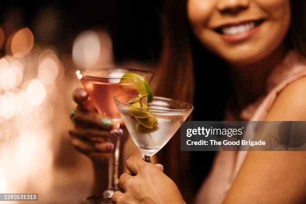 woman toasting glasses with date at bar - martini glass stock-fotos und bilder