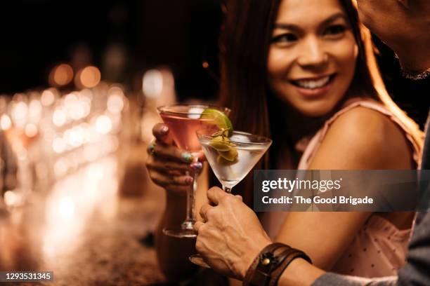 smiling woman enjoying cocktail with male friend at bar - verführung stock-fotos und bilder