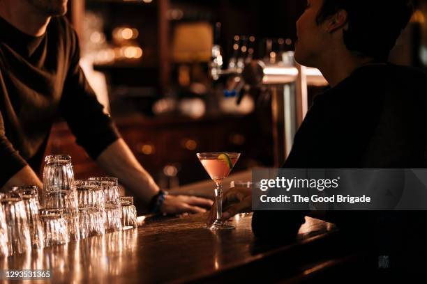 bartender talking to female customer at bar counter - bartender stock pictures, royalty-free photos & images