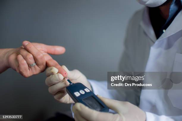 doctor measuring blood glucose of woman in his home. - glycemia stock pictures, royalty-free photos & images