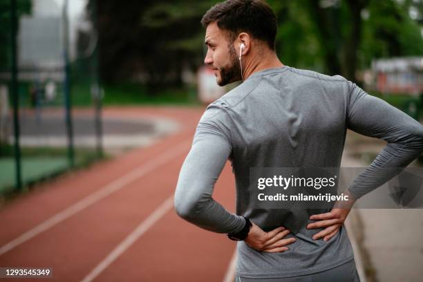 deportista sufriendo de dolor de espalda en el parque al aire libre - musculo fotografías e imágenes de stock