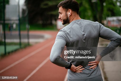Sportivo affetto da mal di schiena al parco all'aperto Sportivo affetto da mal di schiena al parco all'aperto