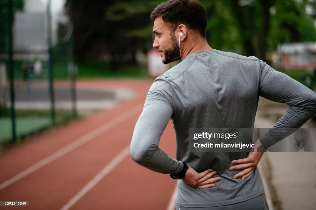 Sportsman suffering from backache at park outdoors