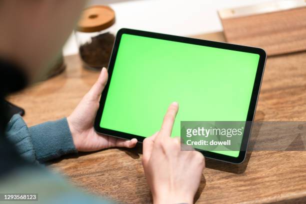 female using digital tablet with green screen - tablet pc stock-fotos und bilder