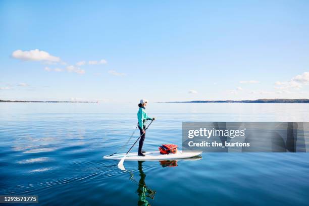 woman paddle boarding on the sea, the blue sky is reflected in the smooth water - paddleboarding 個照片及圖片檔