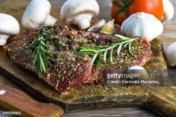 raw beef steak served with vegetables and herbs on rustic wooden board background - marinated stock pictures, royalty-free photos & images